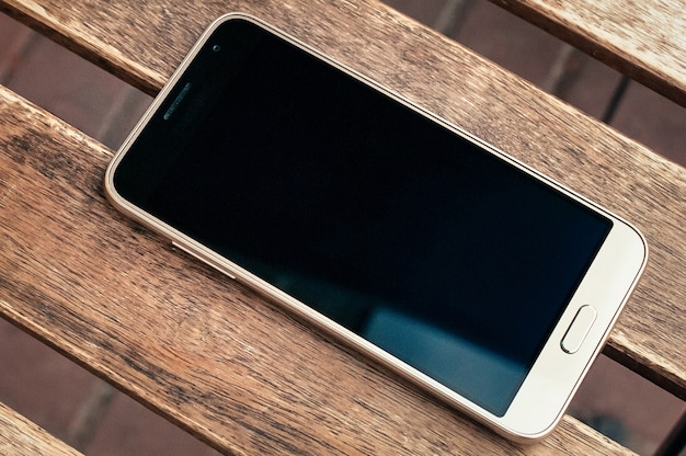 smartphone com tela preta na mesa de madeira, vista superior