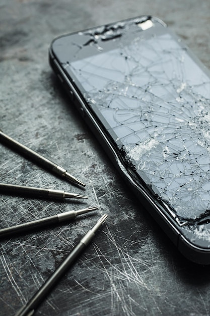 Foto smartphone com uma tela quebrada e ferramentas de reparo closeup