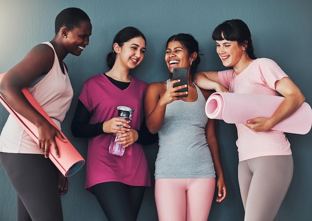 Smartphone de amigos de fitness e meme engraçado na comunicação de mídia social e mulheres em grupo de treino em ioga juntas Aplicativo móvel de tapete de exercícios e conexão com riso e saúde on-line de comédia