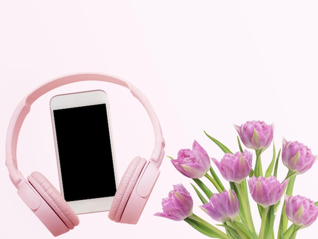 Smartphone de fone de ouvido rosa e flores de tulipas em fundo rosa