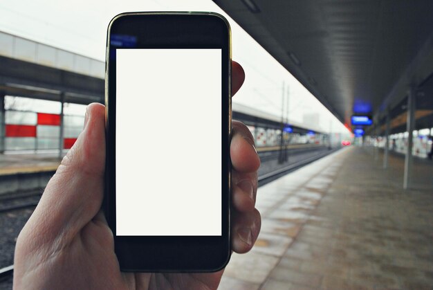 Smartphone de mão com fundo de estação de metrô