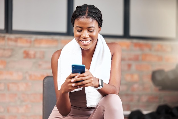 Smartphone de mulher negra e exercício em conexão de academia e mídia social Atleta feminina jamaicana e telefone para comunicação relaxam e quebram após treino de fitness e treinamento para saúde ou sorriso