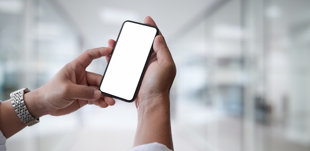 Smartphone des leeren Bildschirms in der Hand des jungen Mannes im Büro