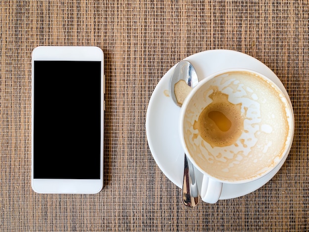 Smartphone e copo de café vazio na mesa de madeira na vista superior