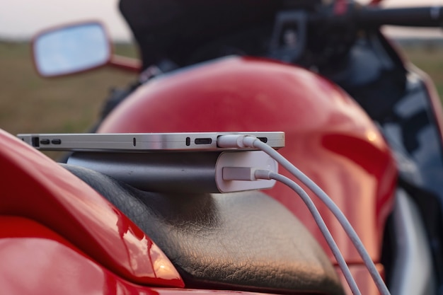 Smartphone em uma motocicleta e Power Bank carrega o telefone contra o pano de fundo da natureza.