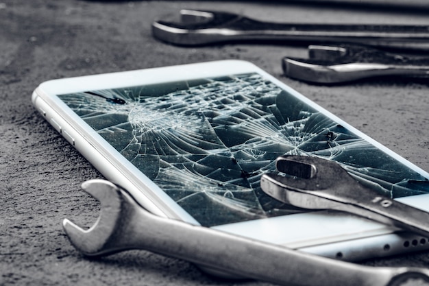 Foto smartphone estrellado con herramientas de reparación en gris
