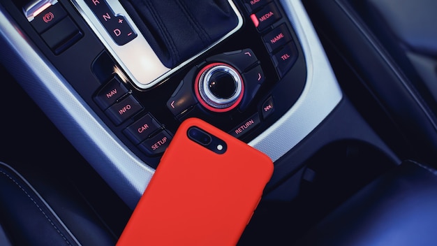 Smartphone en estuche rojo con doble cámara en el interior de un automóvil de lujo moderno