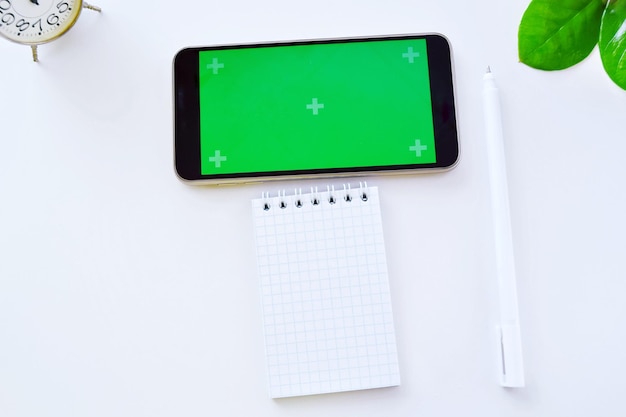 Smartphone-Green-Screen-Mockup und schwarzer Stift mit Notizblock Technologiekonzept von Notizblock-Stift und Smartphone-Blogger im Sommer
