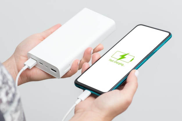 Smartphone in den Händen der Frau wird von der Powerbank aufgeladen