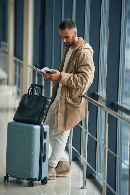 Smartphone in der Hand Junger hübscher Mann am Flughafen