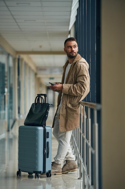 Smartphone in der Hand Junger hübscher Mann am Flughafen