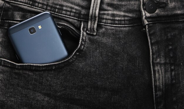 Smartphone in der Vordertasche der schwarzen Jeans