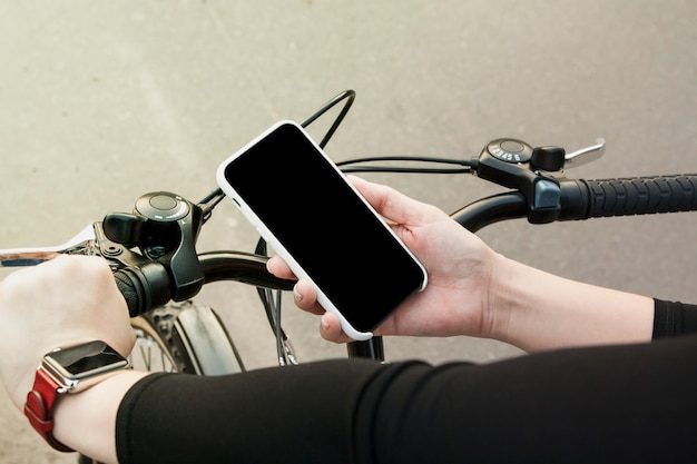 Smartphone en una mano femenina en bicicleta