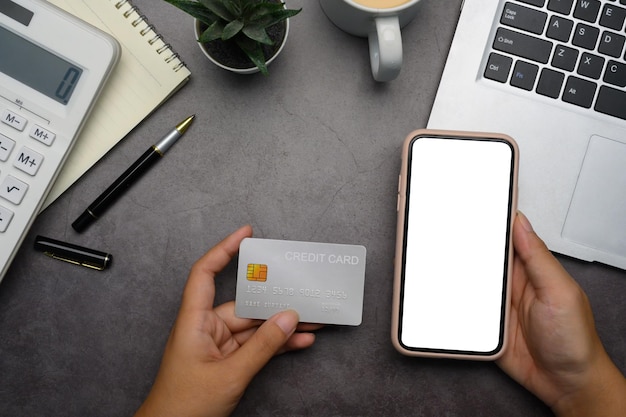 Smartphone en la mano con pantalla en blanco una tarjeta de crédito compras en línea transacciones financieras y comercio electrónico