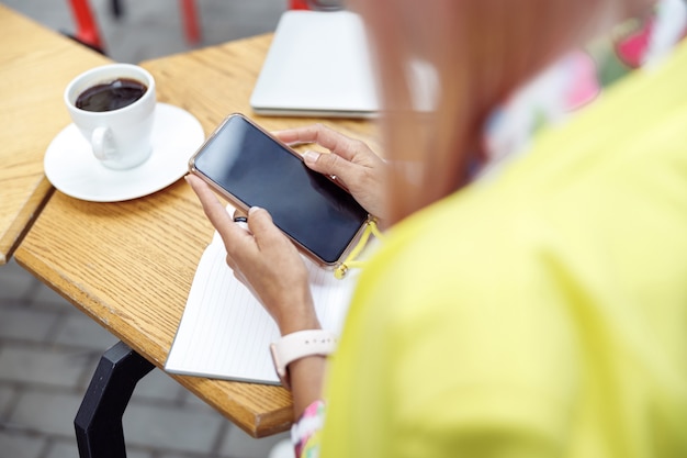 Smartphone en manos del visitante de la cafetería tomando café