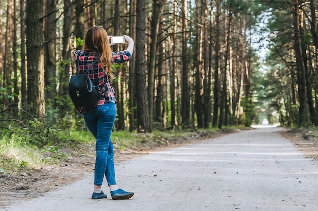 Smartphone maquete nas mãos Meninas na floresta, num contexto de árvores. Conceito sobre o tema da recreação ao ar livre de viagens.