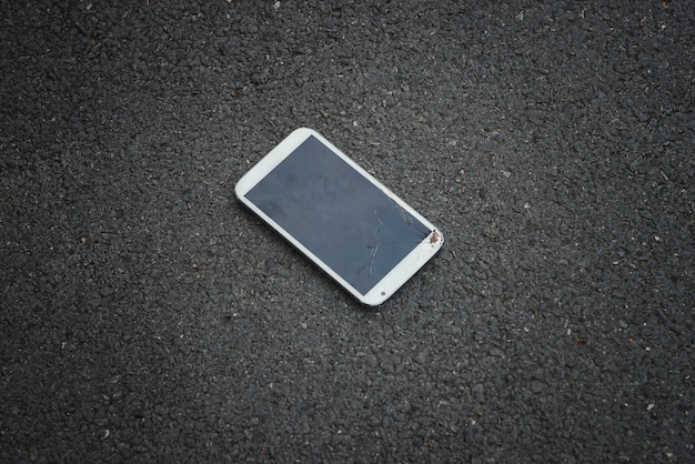 Smartphone mit dem gebrochenen Bildschirm, der auf der Straße liegt