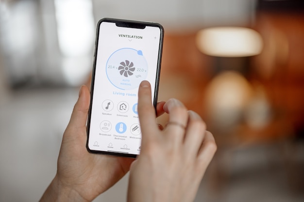 Smartphone mit gestarteter Anwendung zur Belüftungsanpassung, Überwachung der Luftqualität. Gesundheitsmikroklima zu Hause Konzept.