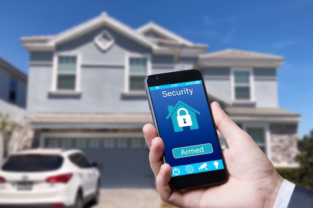 Smartphone mit Home-Security-App in der Hand auf dem Hintergrund des Gebäudes