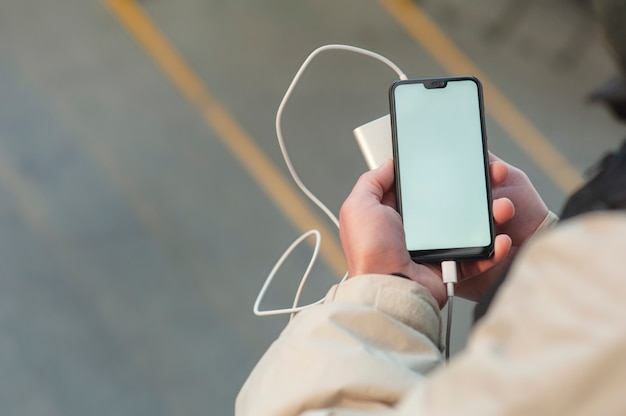 Smartphone mit tragbarer Aufladung in den Händen eines Mannes.