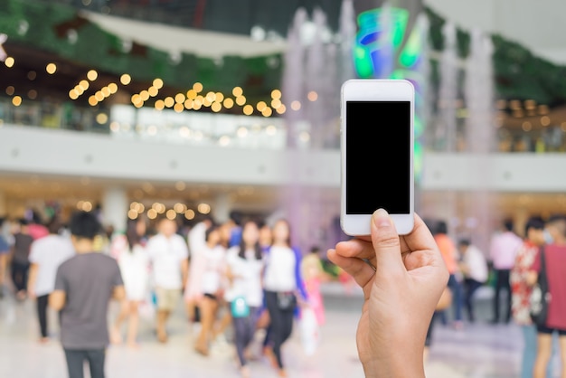 Smartphone mit weißen Bildschirm in der Hand auf verschwommen in Shopping-Mall Hintergrund, Shopping-Online-Konzept, Einkaufen von Smartphone