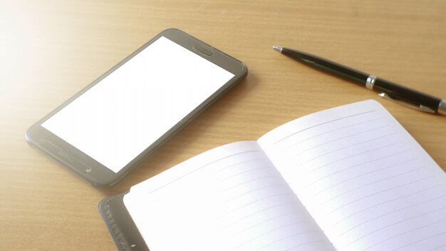 smartphone móvel com tela branca e notebook memo na mesa de trabalho