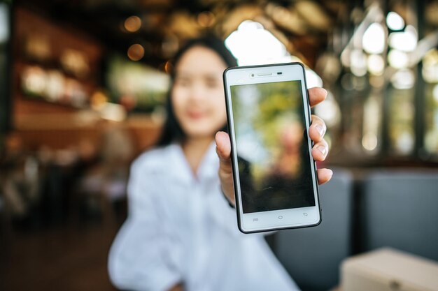 Foto smartphone con mujer sosteniendo con la mano izquierda en el café