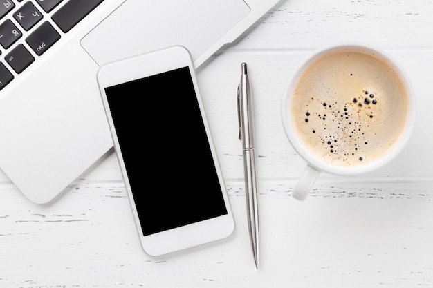 Smartphone na mesa de trabalho do escritório com xícara de café e laptop. Flat lay. Vista superior com espaço para o seu texto