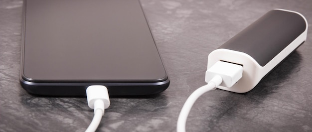 Smartphone negro con enchufe blanco conectado de banco de energía externo Carga de teléfono móvil