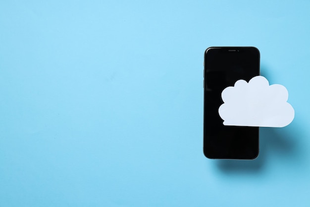 Smartphone negro con una nube de papel en un fondo azul lugar para el texto