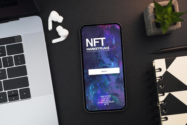 Smartphone con NFT NonFungible Token Marketplace en la pantalla sobre una mesa de fondo negro Entorno de oficina Crypto art