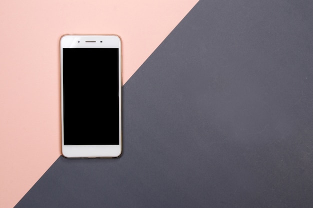 Smartphone ou telefone celular no fundo cor-de-rosa e cinzento com espaço da cópia.