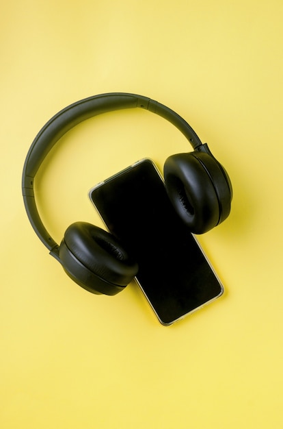 Smartphone con pantalla en blanco con auriculares en papel amarillo