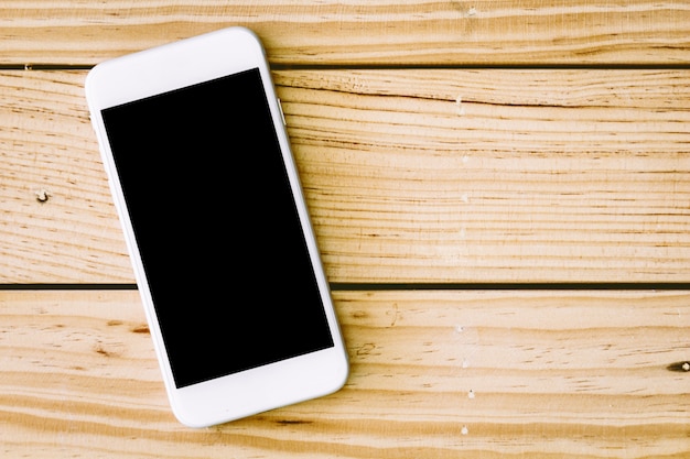 Smartphone de pantalla en blanco en la mesa de madera