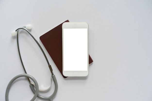 Smartphone de pantalla en blanco para su diseño con pasaporte y estetoscopio para el concepto de control de salud