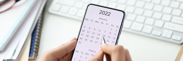 Smartphone en pantalla con calendario para bolígrafo en manos femeninas planeando ideas de negocios por concepto