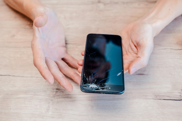 Smartphone con pantalla rota en manos de un joven