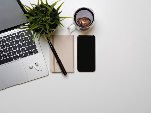 Smartphone y portátil en una mesa blanca