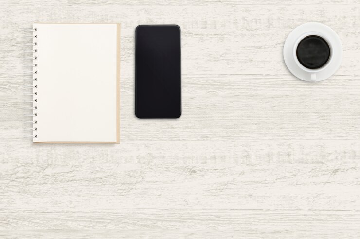 Foto smartphone con portátil y una taza de café en madera.