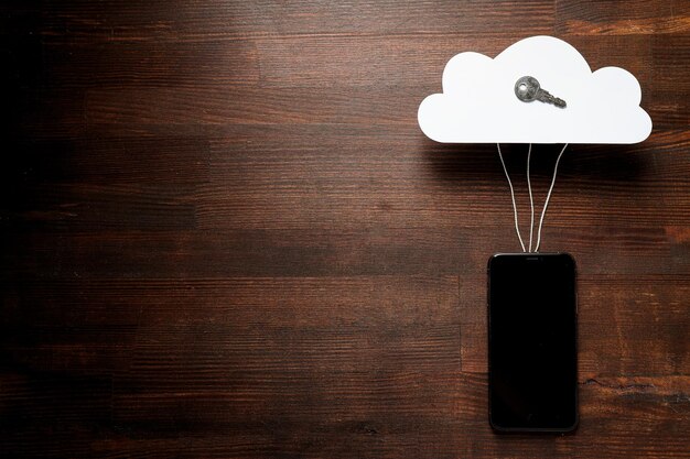 Smartphone preto com uma nuvem de papel em um lugar de conceito de computação em nuvem de fundo escuro para texto