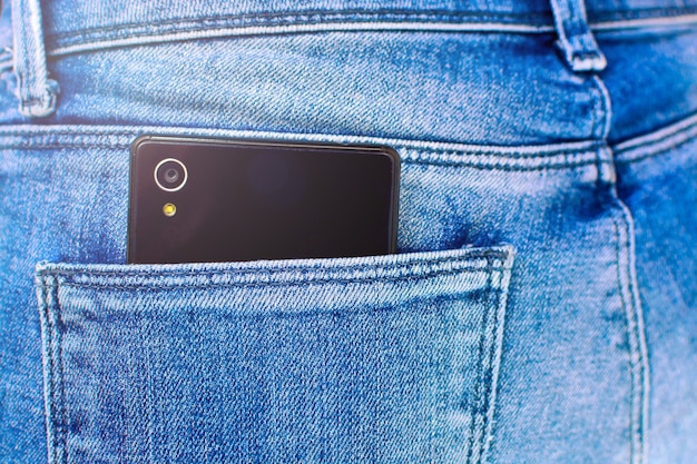 Smartphone preto no bolso de trás da calça jeans da menina