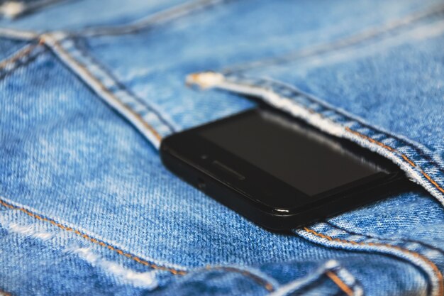 Smartphone preto no bolso traseiro da calça jeans