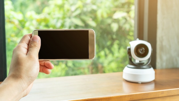 Smartphone que se conecta con la cámara IP de seguridad en una mesa de madera.