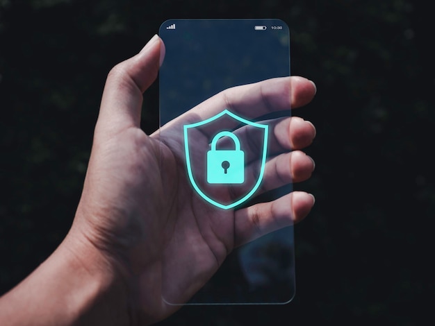 Smartphone-Sicherheits- und Datenschutzkonzept. Blaue Schild- und Schlosssymbolgrafik auf dem Bildschirm eines sehr dünnen futuristischen transparenten Glastelefons in der Hand auf dunklem Hintergrund.