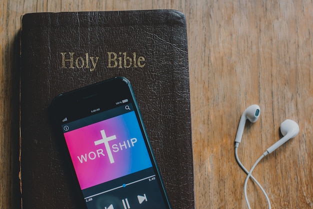 Smartphone sobre la Santa Biblia sobre fondo de madera Adoración a Dios espacio de copia en color vintage