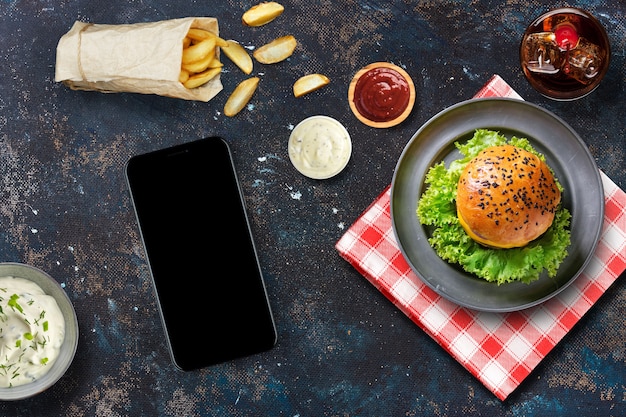 Smartphone und Hamburger auf einem Restauranttisch