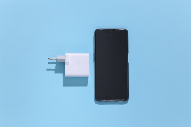 Smartphone- und Ladegerätadapter auf blauem hellem Hintergrund mit tiefem Schatten.