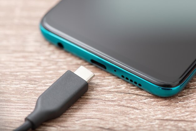 Smartphone und USB-Typ-C-Kabel auf dem Tisch aus nächster Nähe Schnelles modernes Aufladen des Energie- und Stromversorgungskonzepts für Mobiltelefone