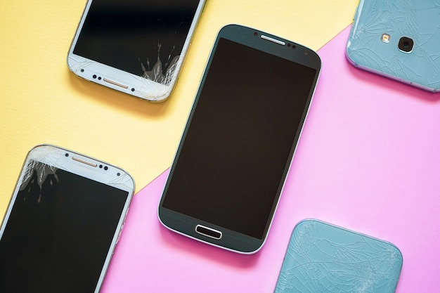 Foto smartphones móviles con pantalla de cristal roto en rosa y amarillo.