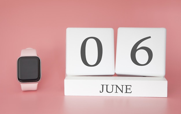 Smartwatch mit Würfelkalender und Datum 06. Juni auf rosa Tisch.